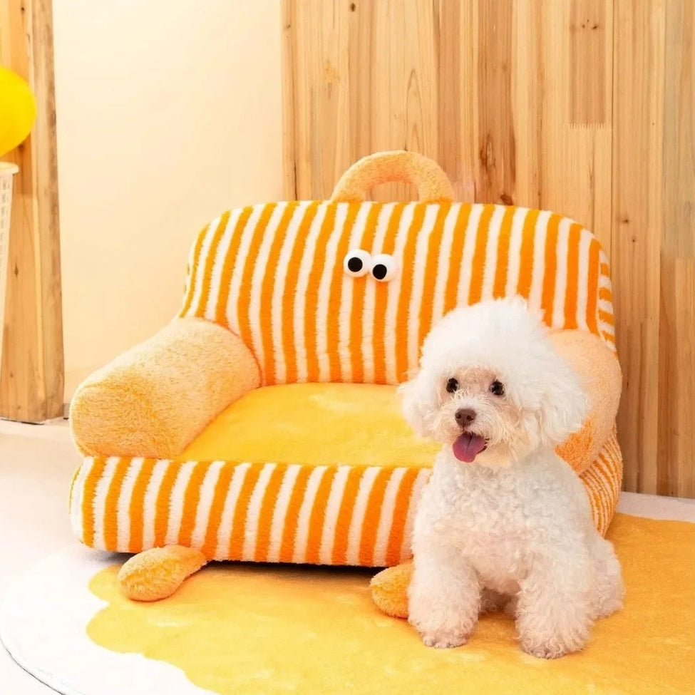 Bichon assis devant un canapé pour chien Rio orange au style chaleureux