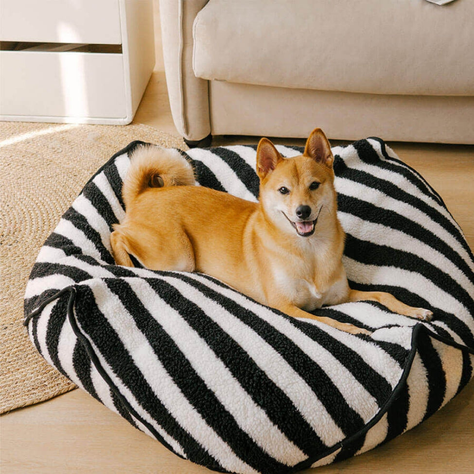 Shiba installé sur un coussin pour chien déhoussable aux rayures noires et blanches