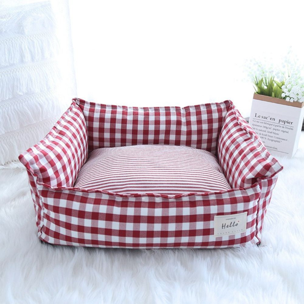 Panier déhoussable pour chien rouge au motif à carreaux présenté seul dans un salon lumineux