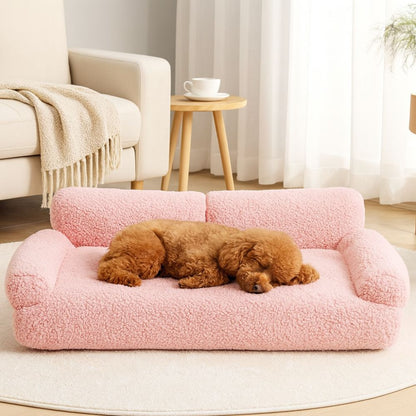 Caniche allongé sur un grand canapé chien rose doté de deux coussins sur le dossier 