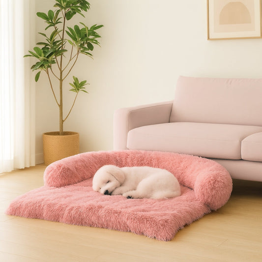 Chiot dort blotti sur un lit canapé pour chien rose, posé au sol