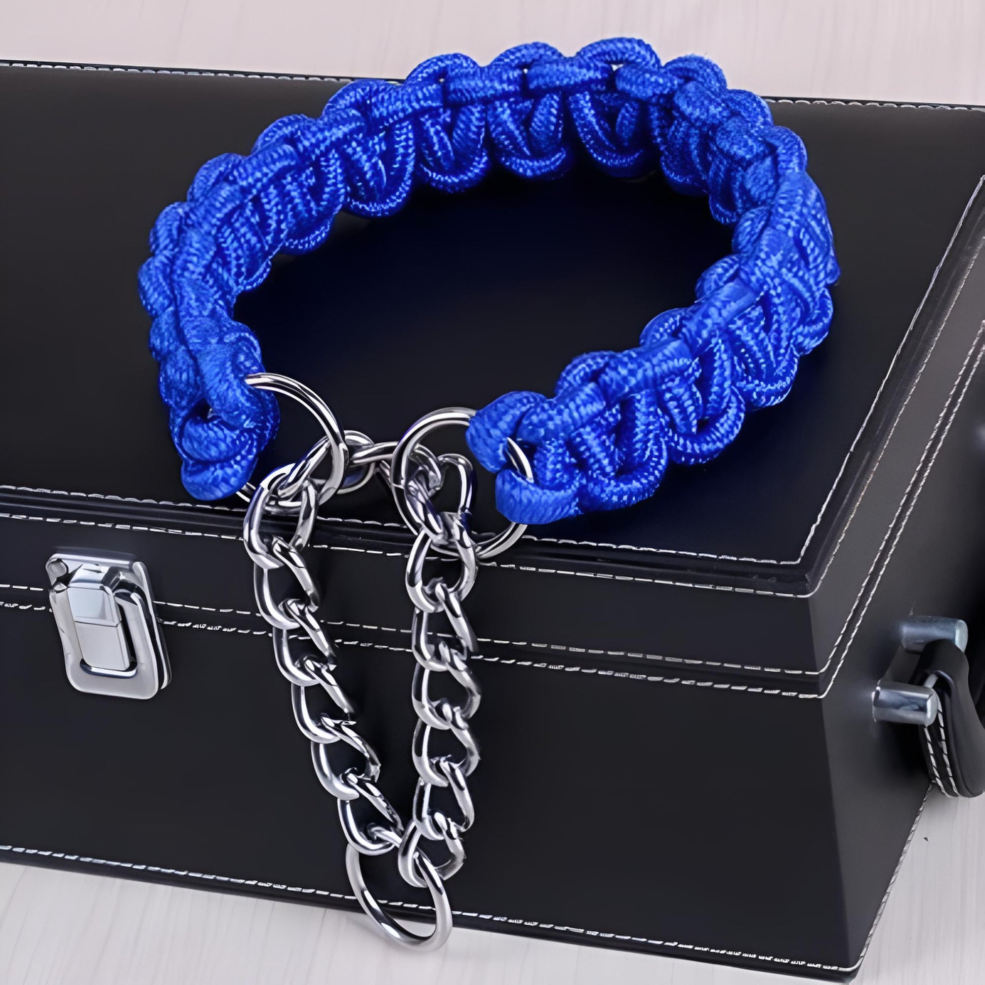 Collier chien paracorde tressé main bleu avec chaîne métallique, posé sur une boîte à bijoux noire