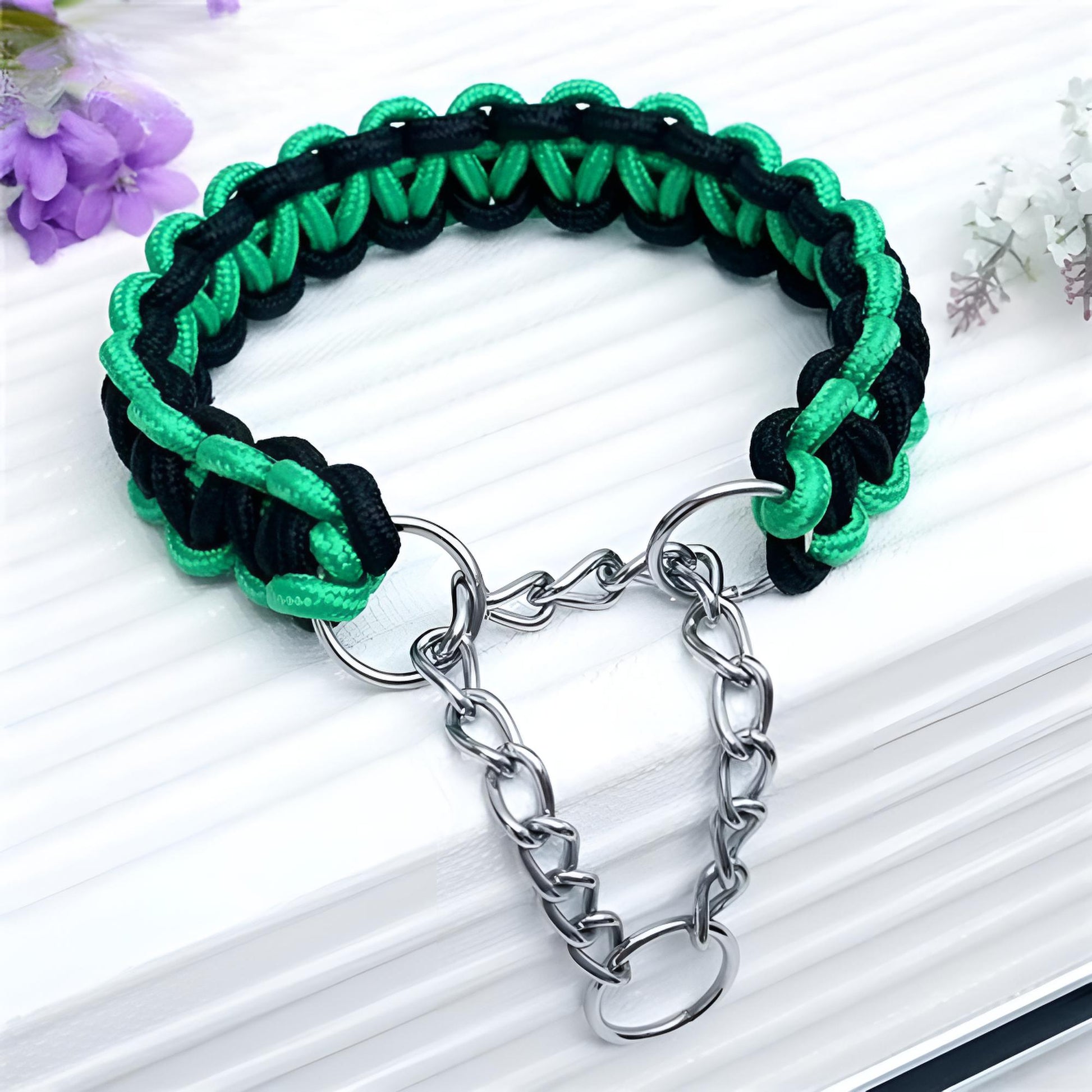 Collier chien paracorde tressé main vert et noir avec chaîne métallique, déposé sur une boîte claire