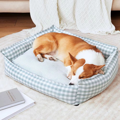 Corgi endormi dans un panier déhoussable pour chien gris sur un coussin à rayures