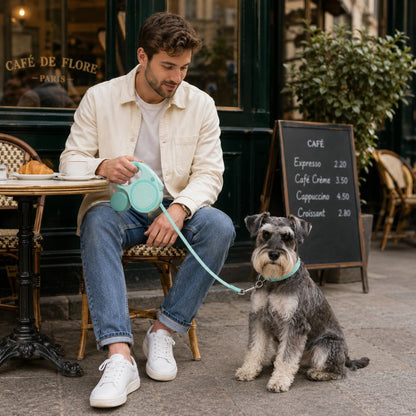 laisse rétractable chien utilisée par un homme avec un schnauzer devant un café parisien