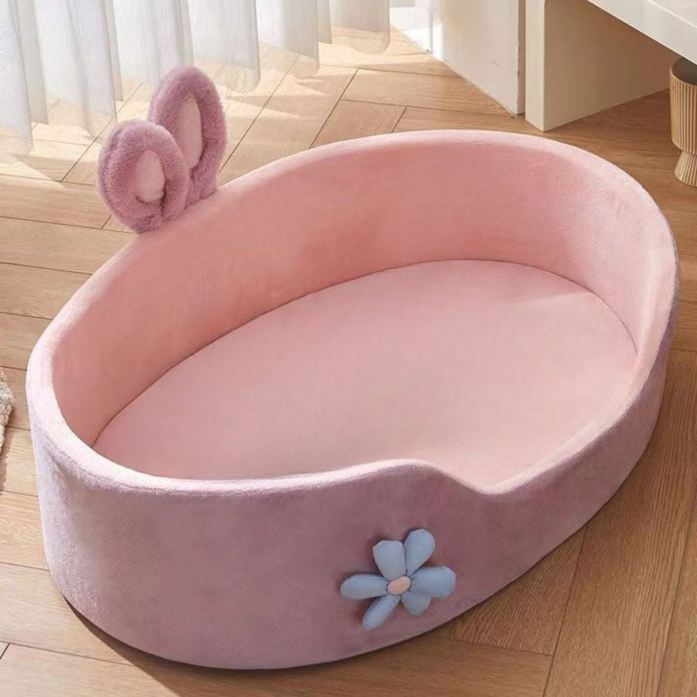 Panier chien design ovale rose avec oreilles en tissu et fleur décorative bleue